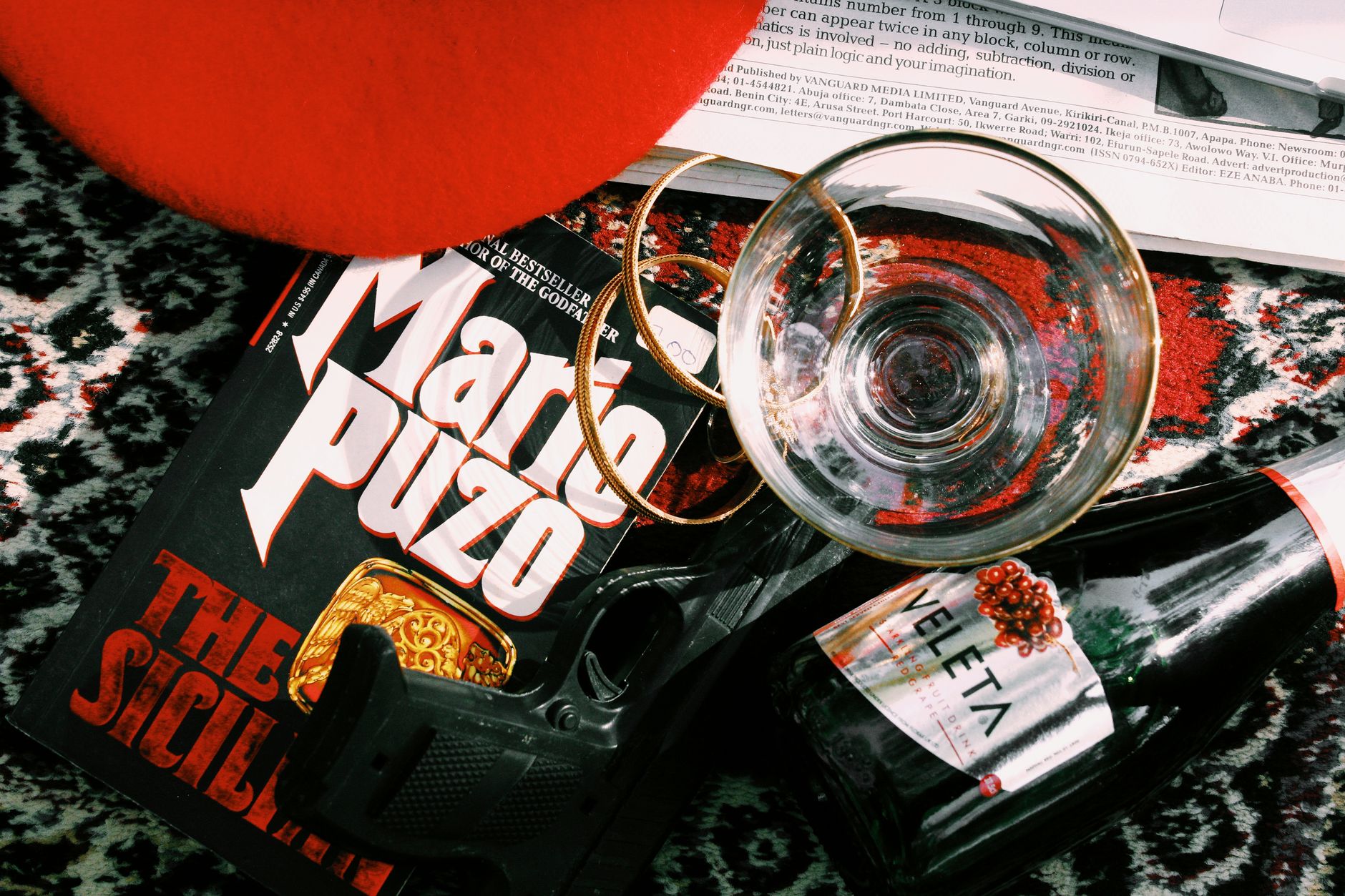 Aerial view of a book, glass, and wine bottle on a patterned surface.