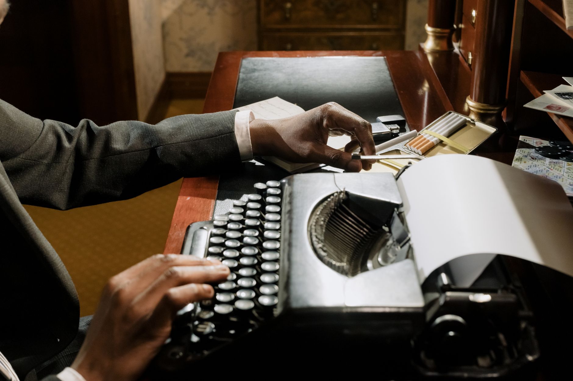 A vintage typewriter in a moody, nostalgic workspace with a person typing.