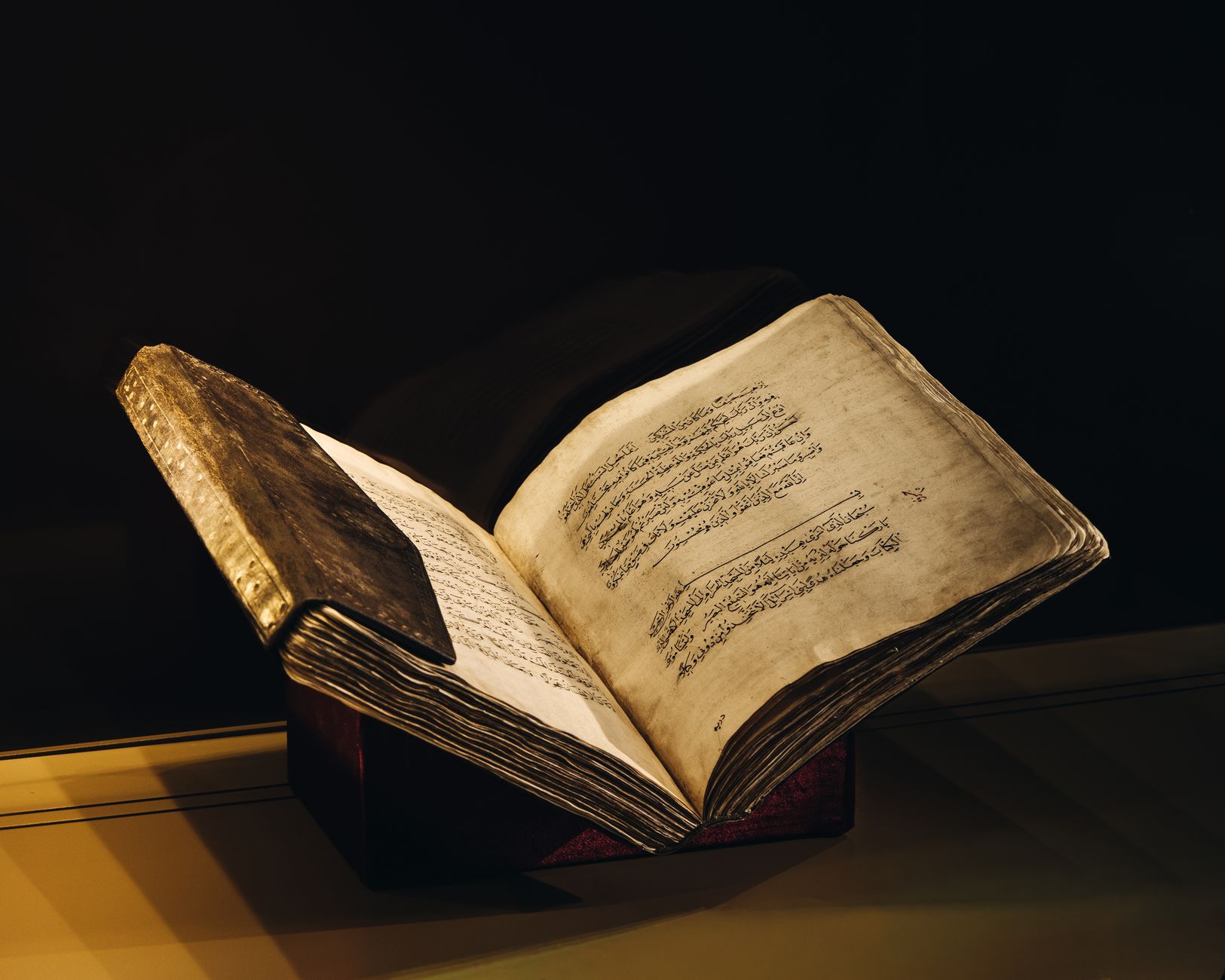 A vintage manuscript with Arabic script open to reveal beautifully aged pages, showcased elegantly.