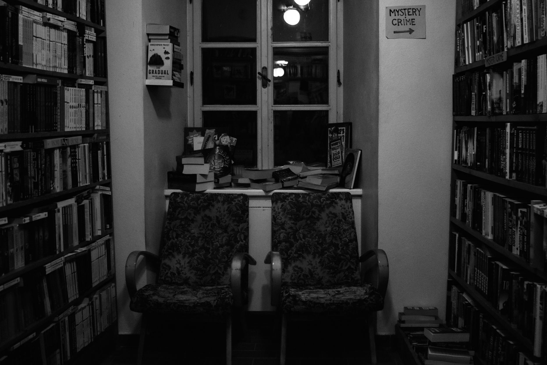 Serene library reading nook with armchairs and mystery book section, perfect for book lovers.