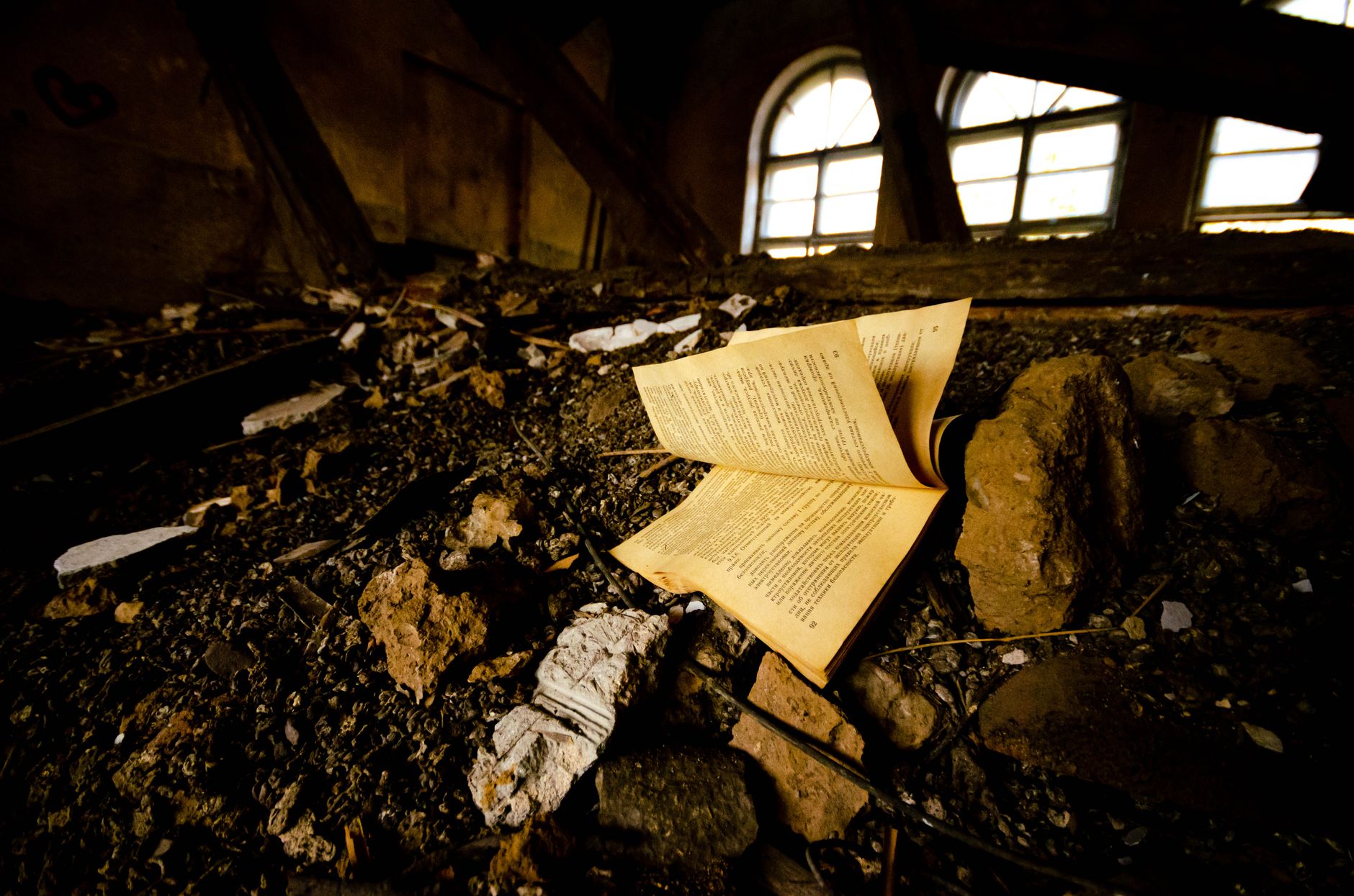An old book lies amidst ruins and decay in an abandoned building.