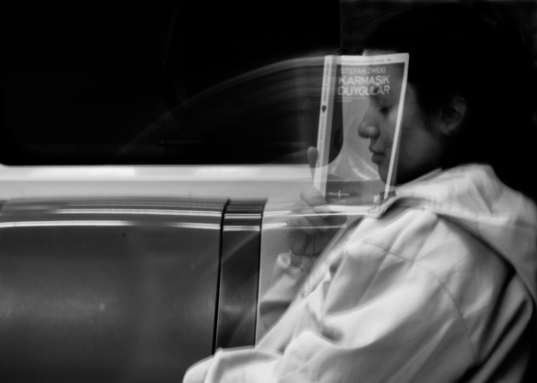 A contemplative black and white portrait on the subway, blending movement and stillness.