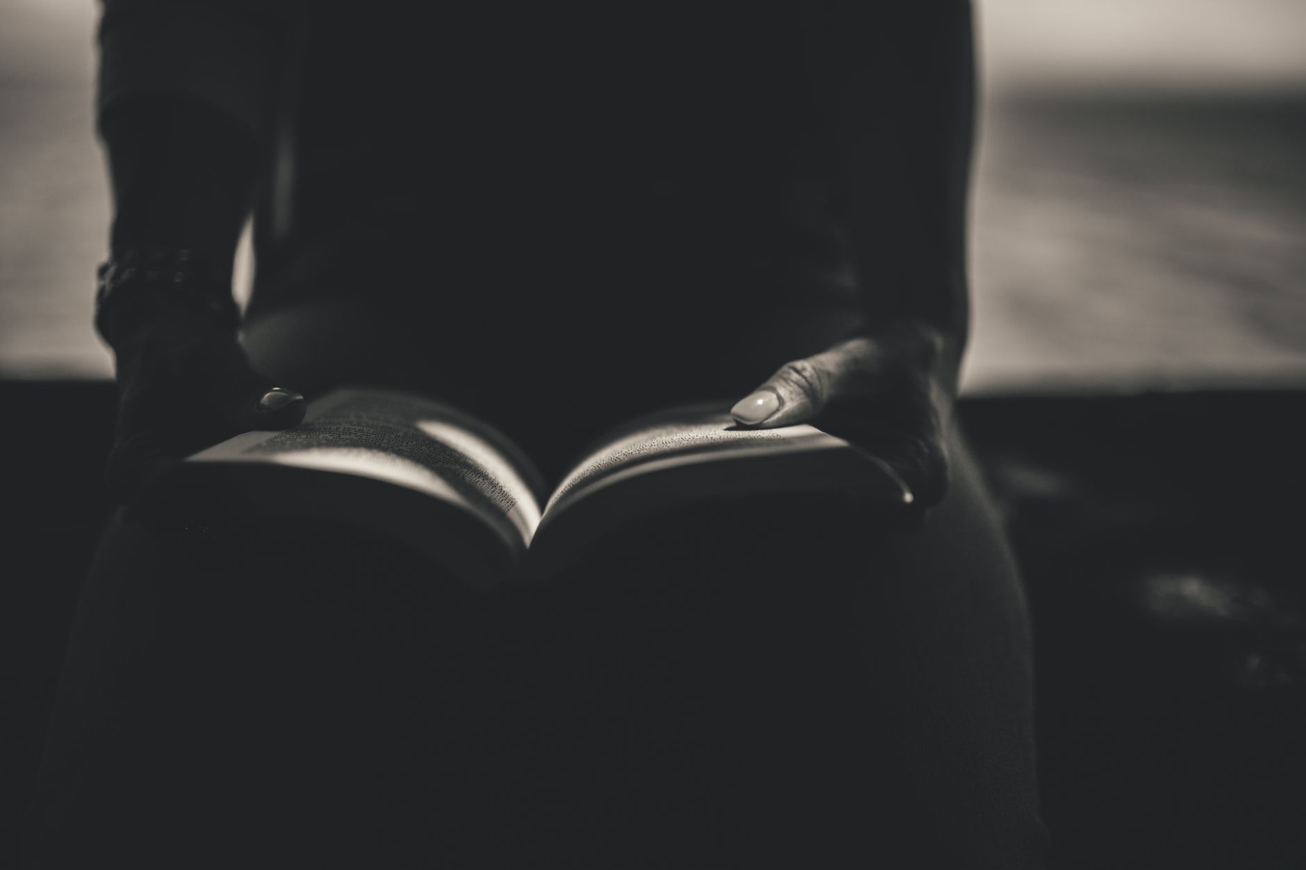 Silhouetted hands holding a book, creating a mysterious reading ambiance.
