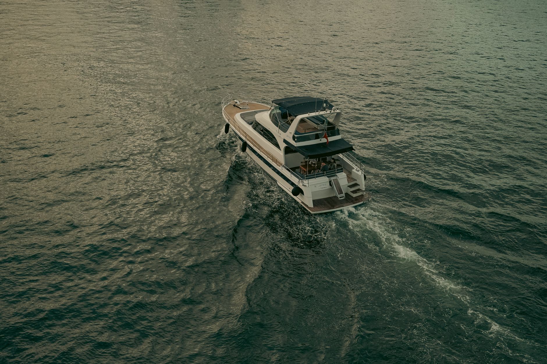 A drone shot capturing a luxury yacht sailing smoothly across the serene and vast sea surface.