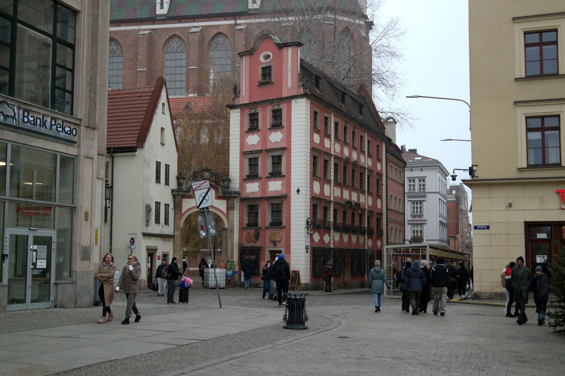 Charming European square with pedestrians, historic buildings, and Gothic church in background.