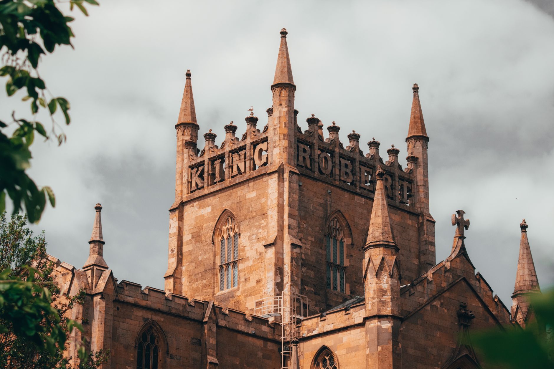 Historic King Robert building against a cloudy sky, showcasing Gothic architecture with prominent towers.