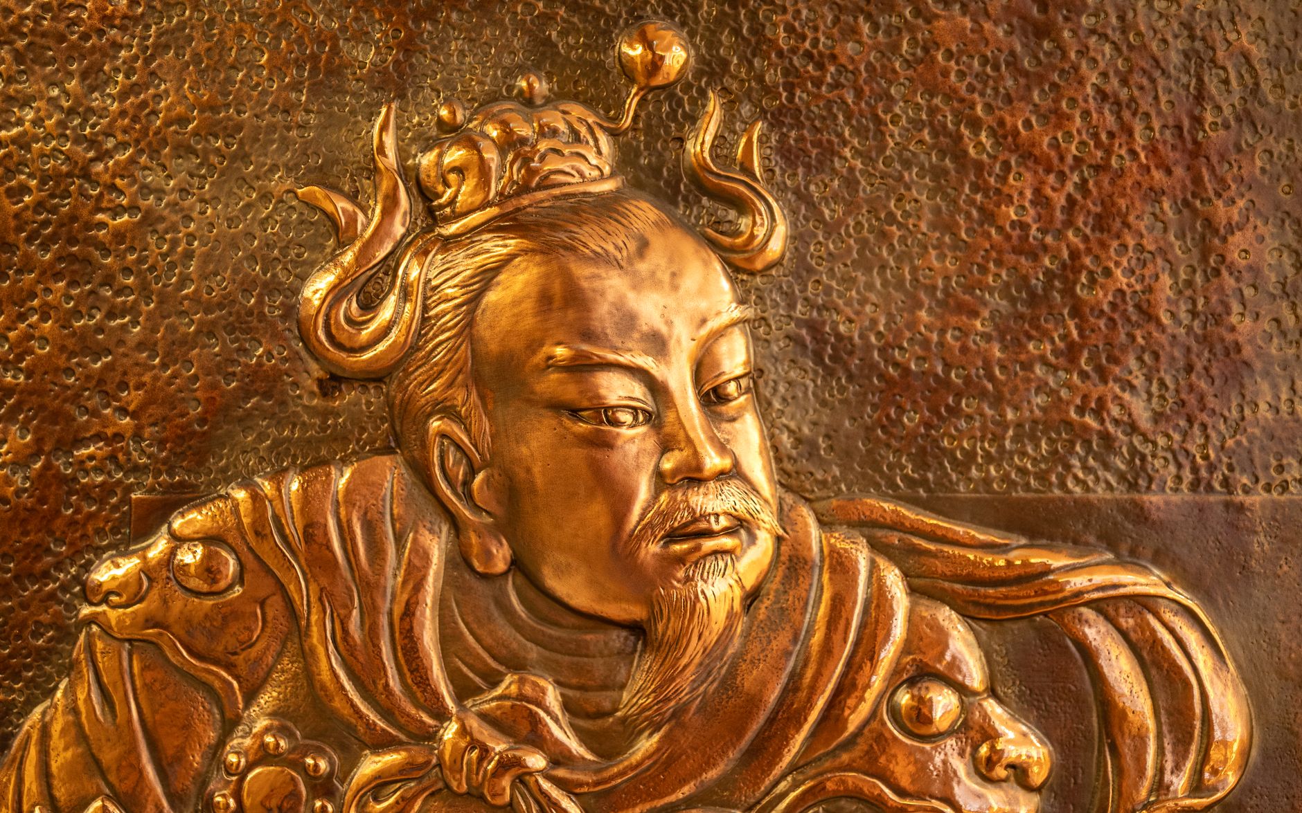 Detailed golden relief depicting an ancient Chinese emperor in traditional attire, showcasing rich texture.