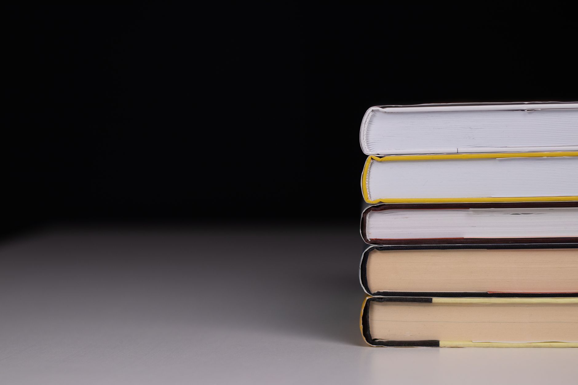 Minimalist stack of hardcover books with a black background and subtle lighting.
