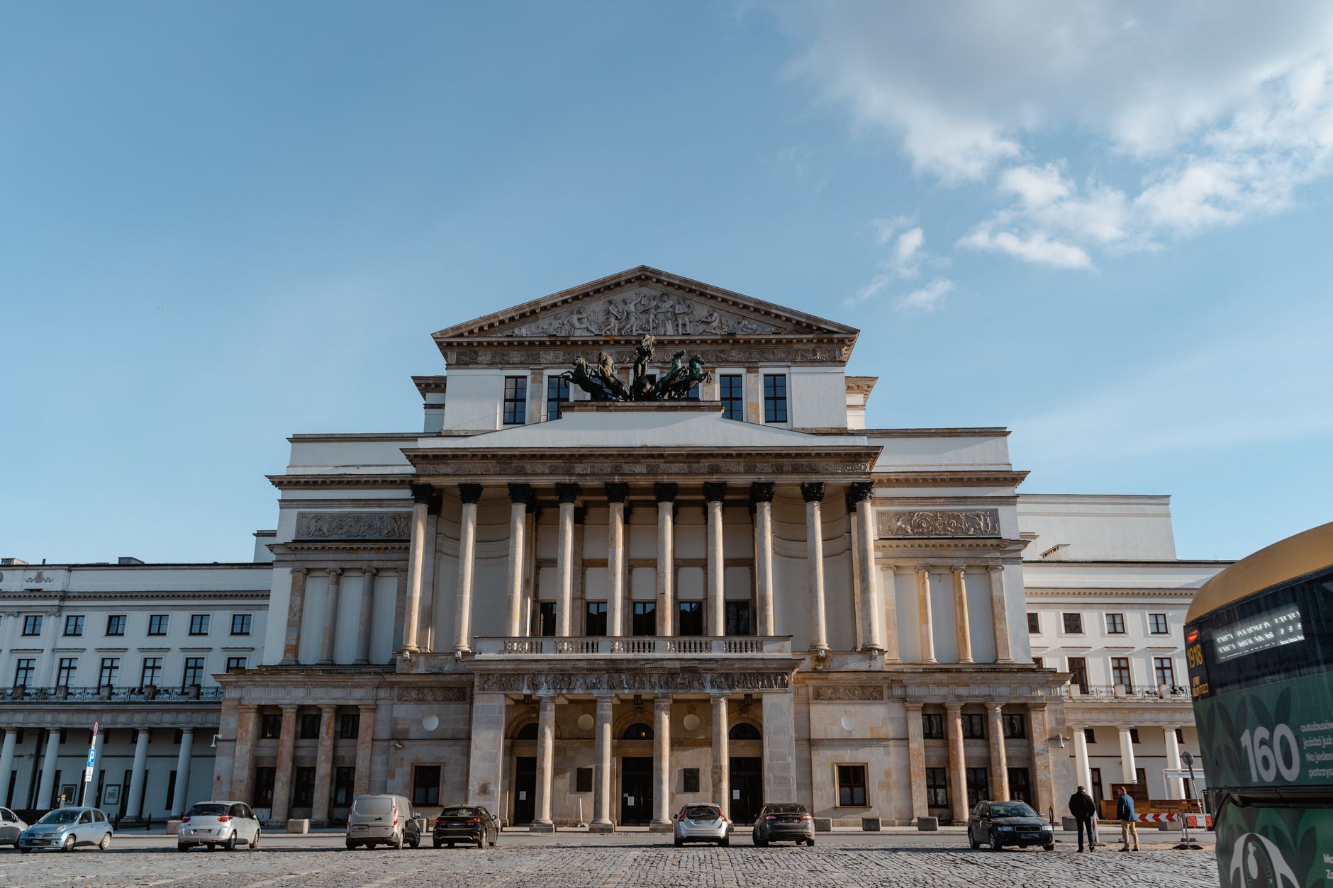 Historic neoclassical theater facade with columns on a sunny day, urban architecture and cultural landmark.
