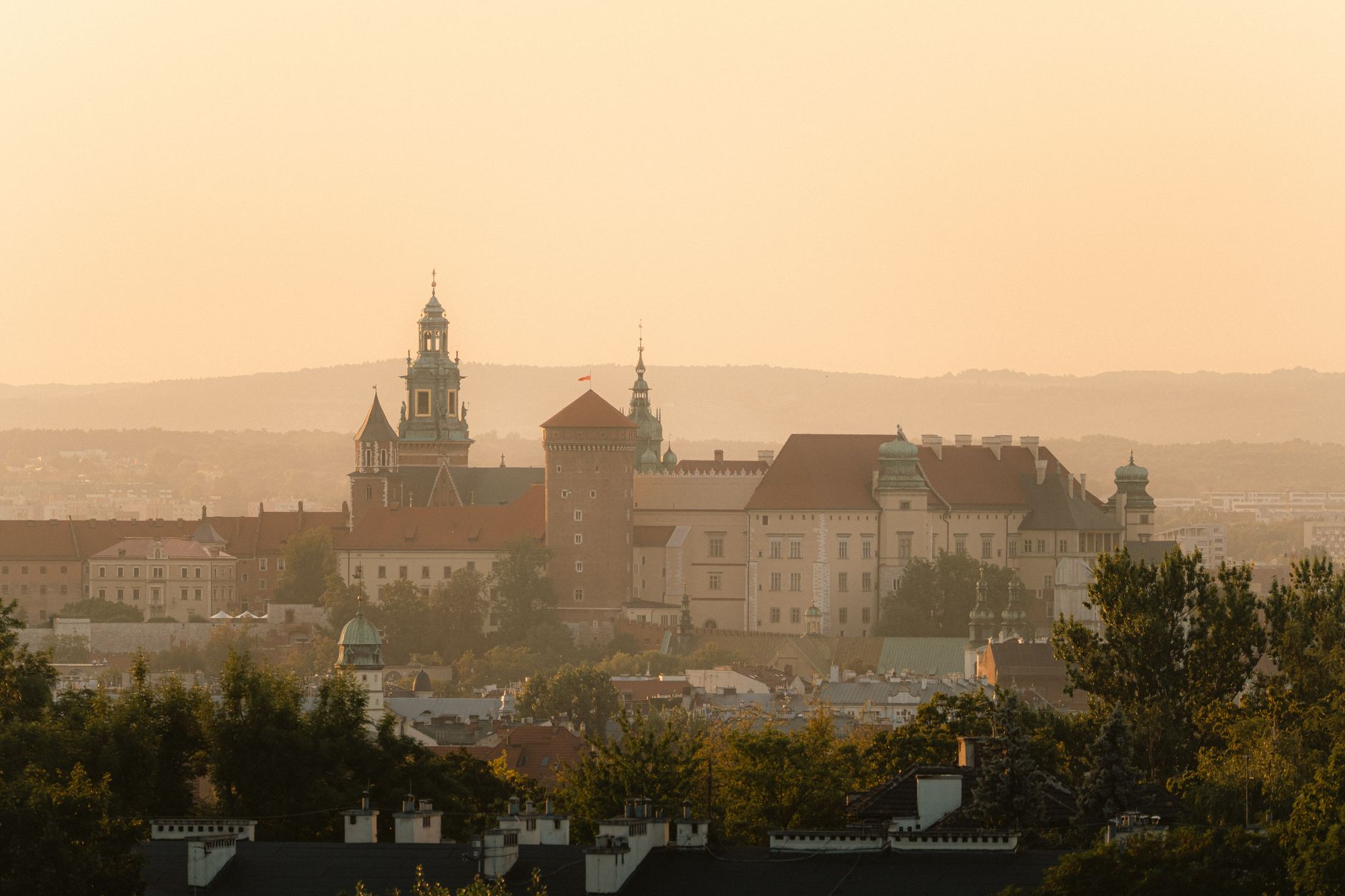 Scenic view of Wawel Castle in Kraków during sunset with a warm, golden glow.