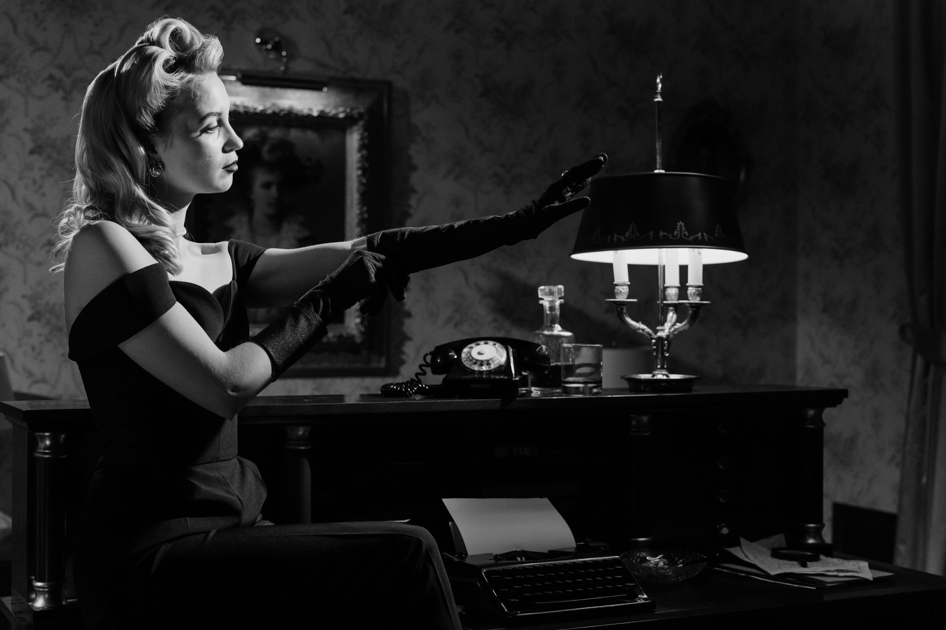 A captivating monochrome portrait of an elegant woman in a vintage noir setting.