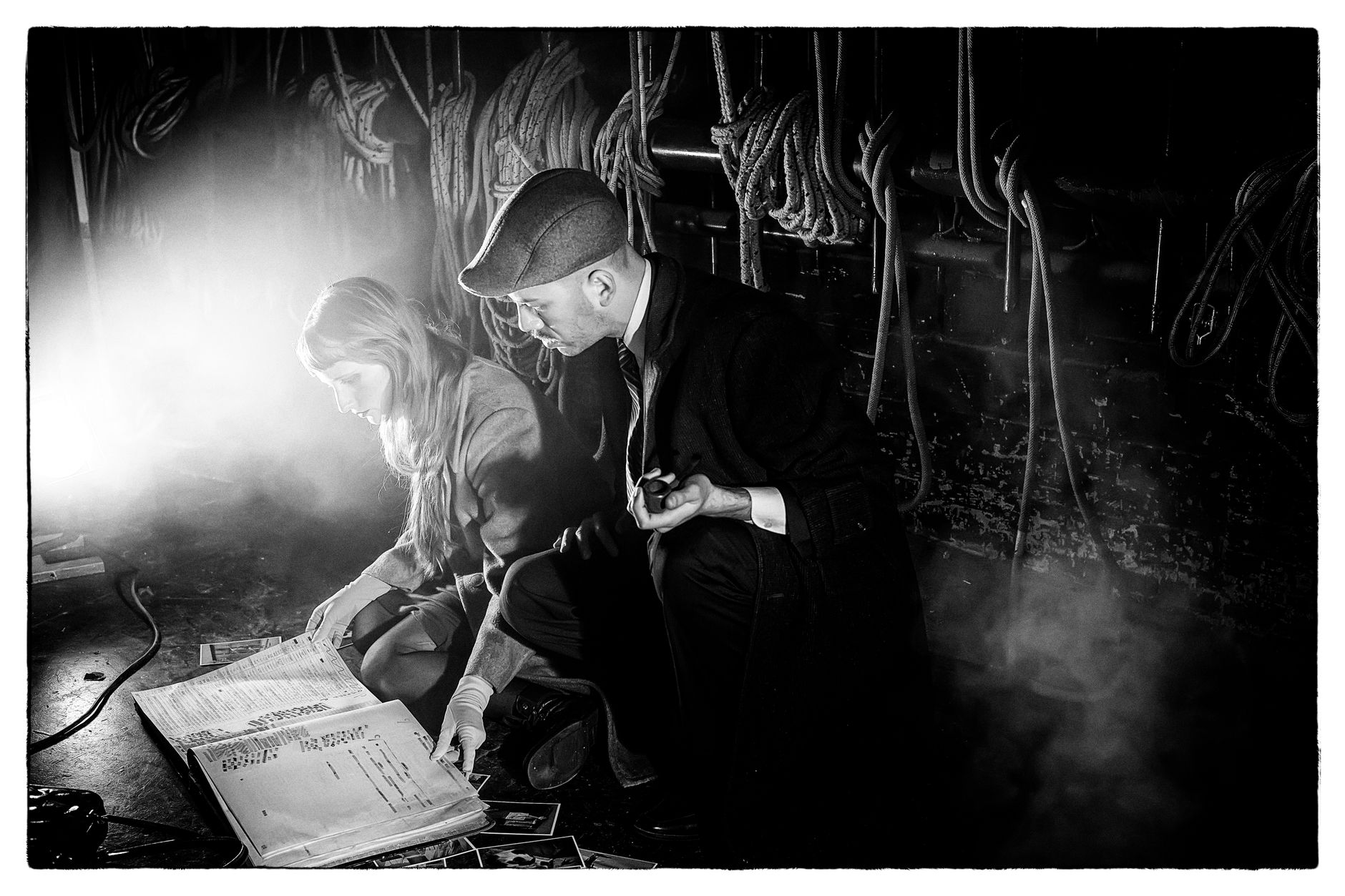 A noir-style scene with two detectives analyzing documents in a dimly lit room.