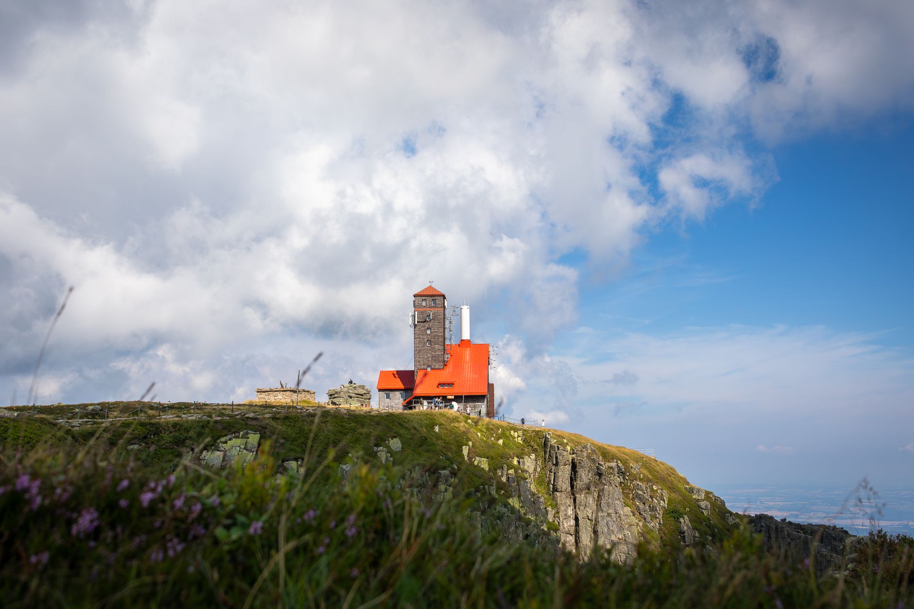 A scenic view of a building atop a mountain in Szklarska Poręba, Poland under a blue sky.