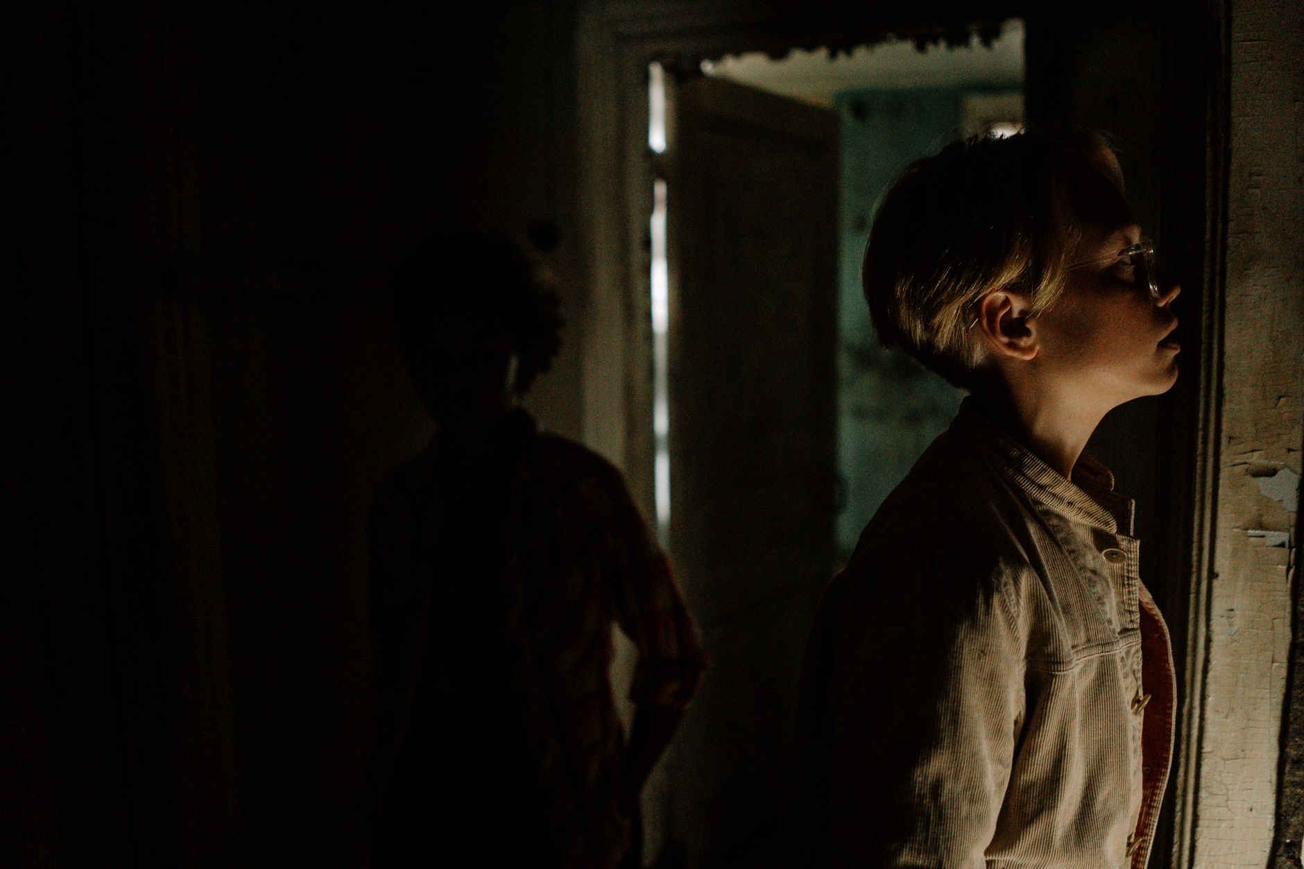 Mysterious and eerie atmosphere in a dimly lit abandoned room with shadowy figures.