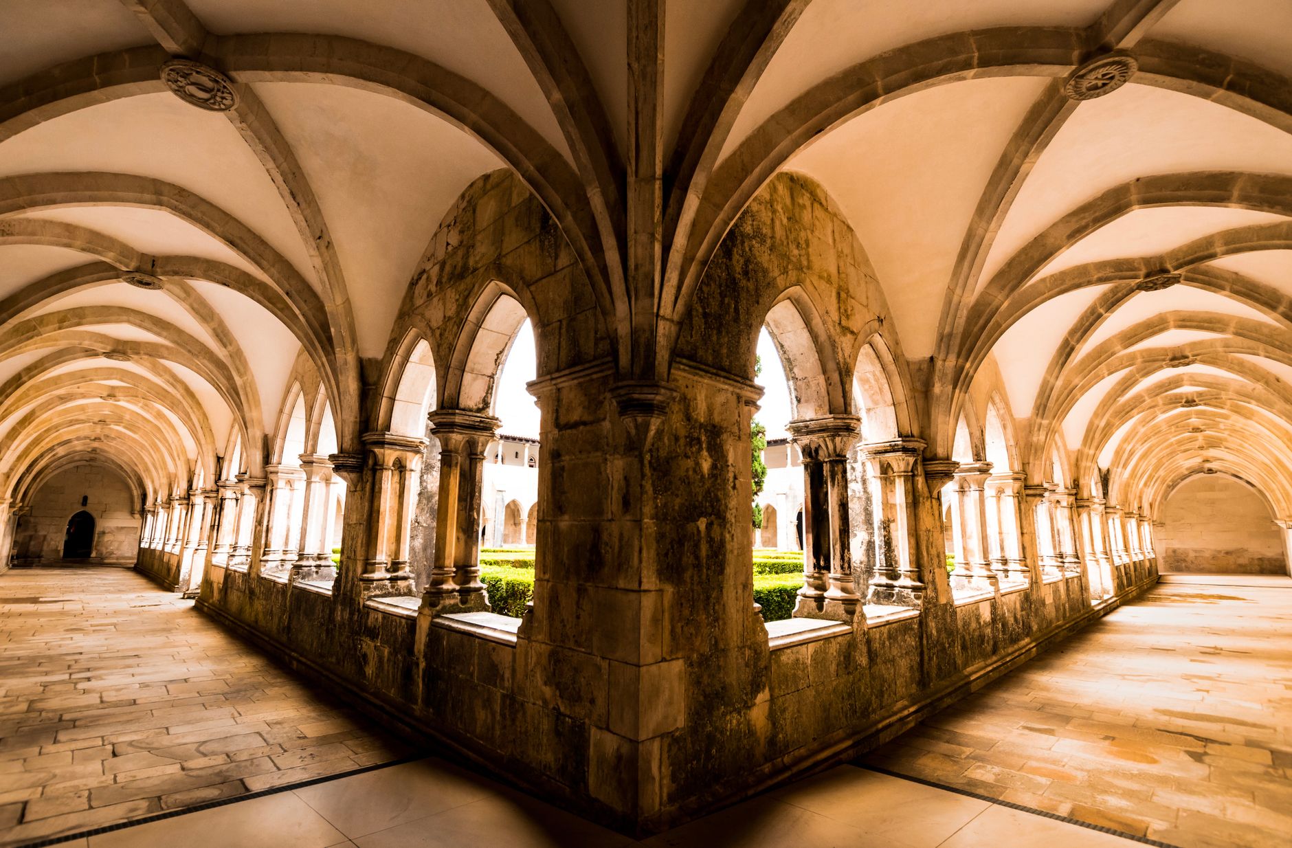 Explore the stunning Gothic architecture of Batalha Monastery's cloisters in Portugal with intricate vaulted ceilings.