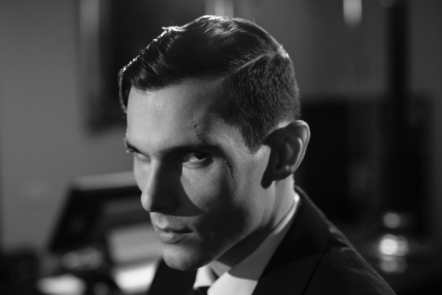 Cinematic black and white portrait of a serious man with a scar and intense expression.