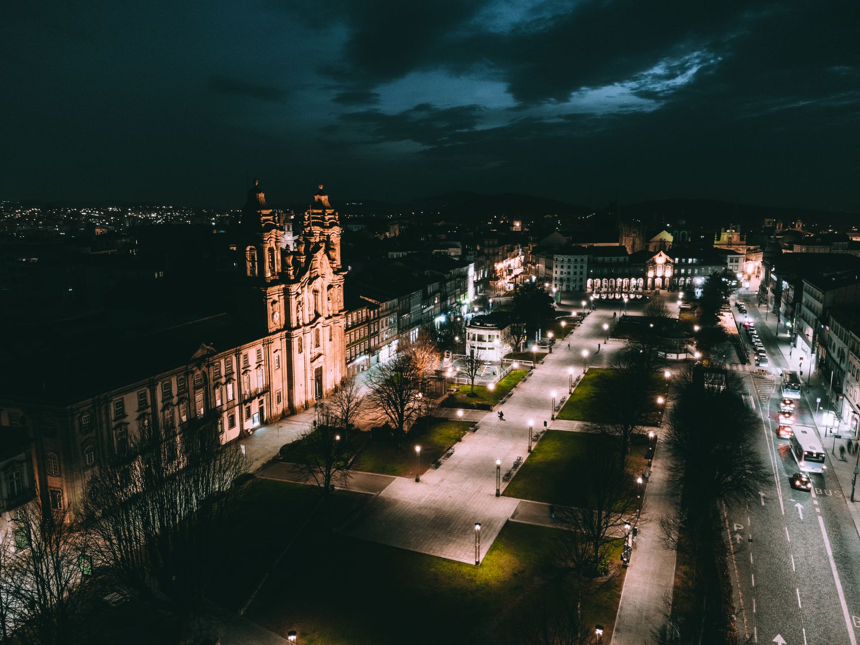 Aerial view of a beautifully illuminated European city square at night, showcasing historic architecture.