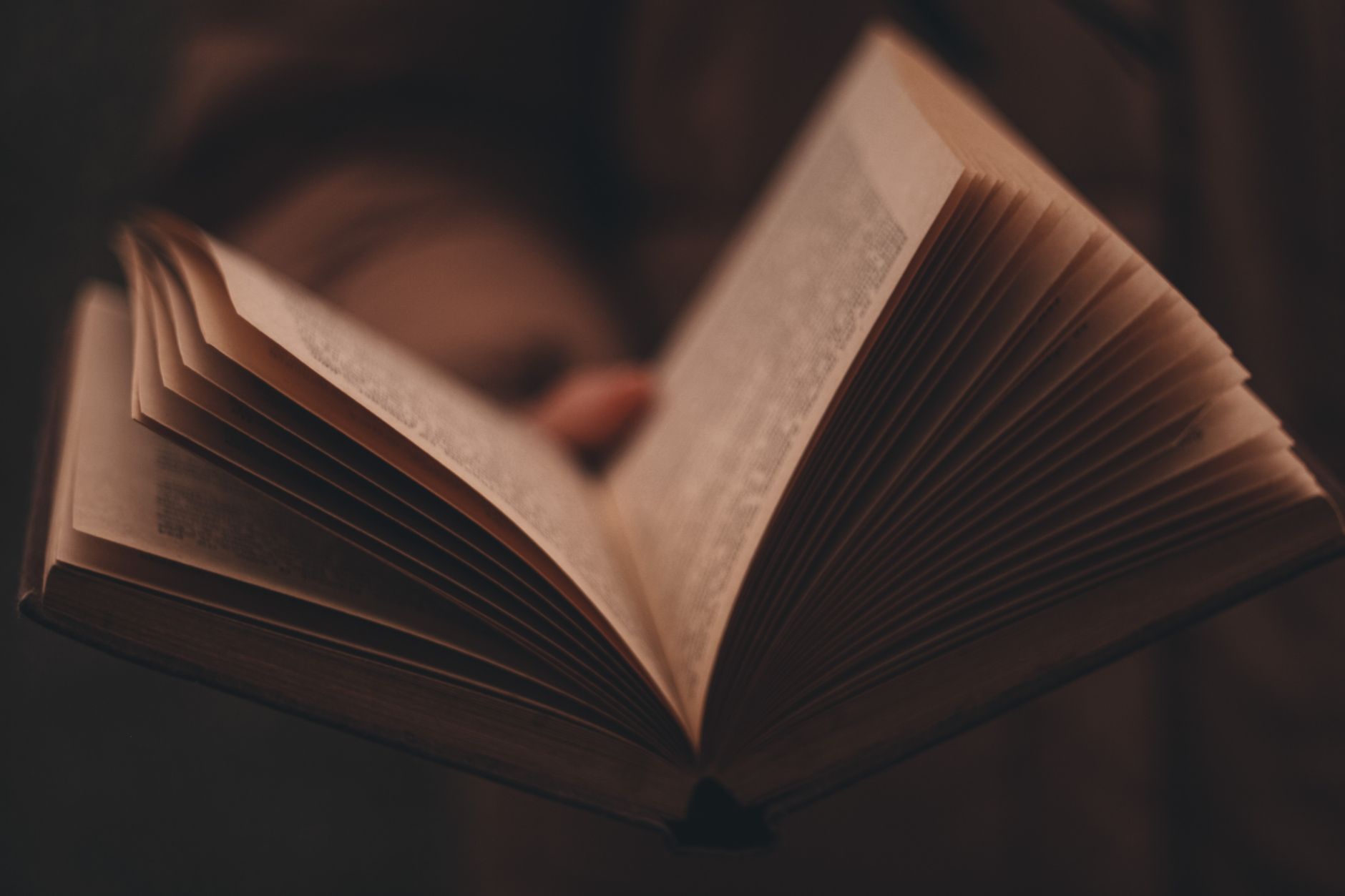 Close-up of an open book with pages fanned out in moody lighting.