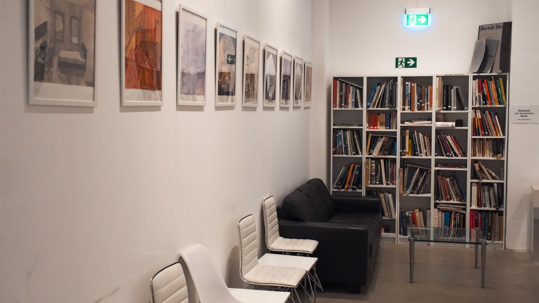 Cozy library corner featuring framed art, chairs, and packed bookshelves, creating a warm and inviting reading space.