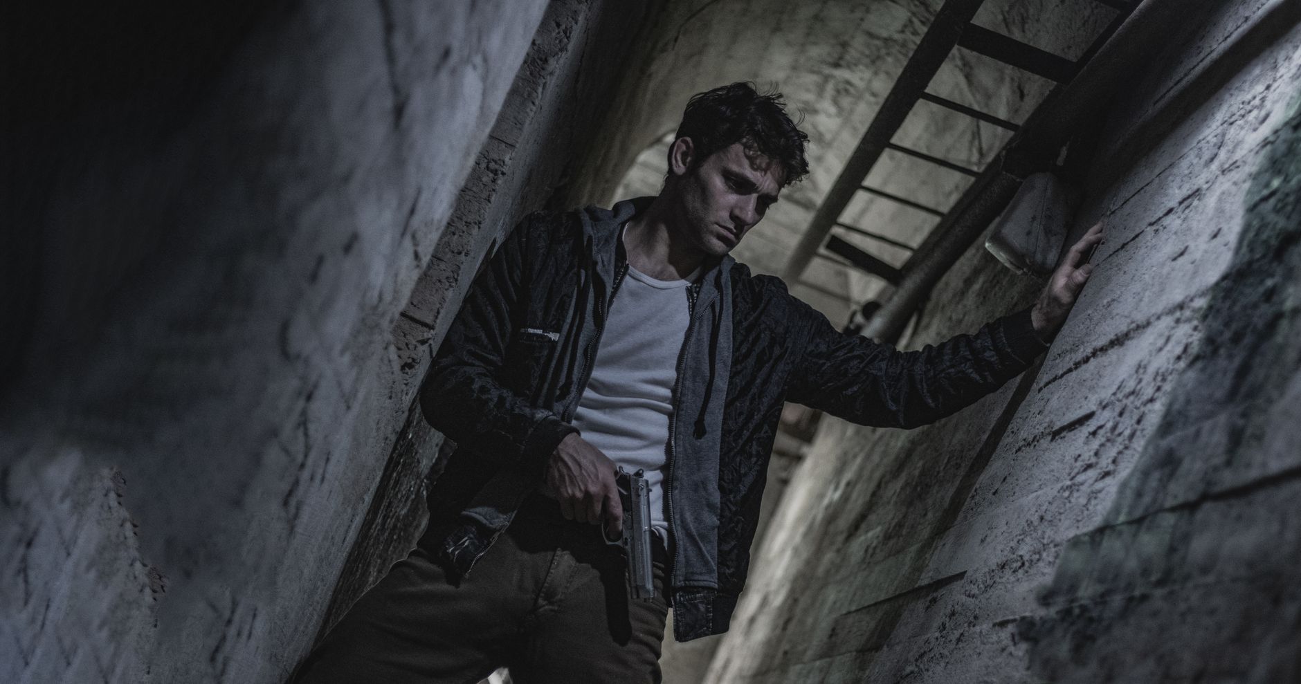 Man with a weapon in a dimly lit alleyway, creating a tense and dramatic atmosphere.