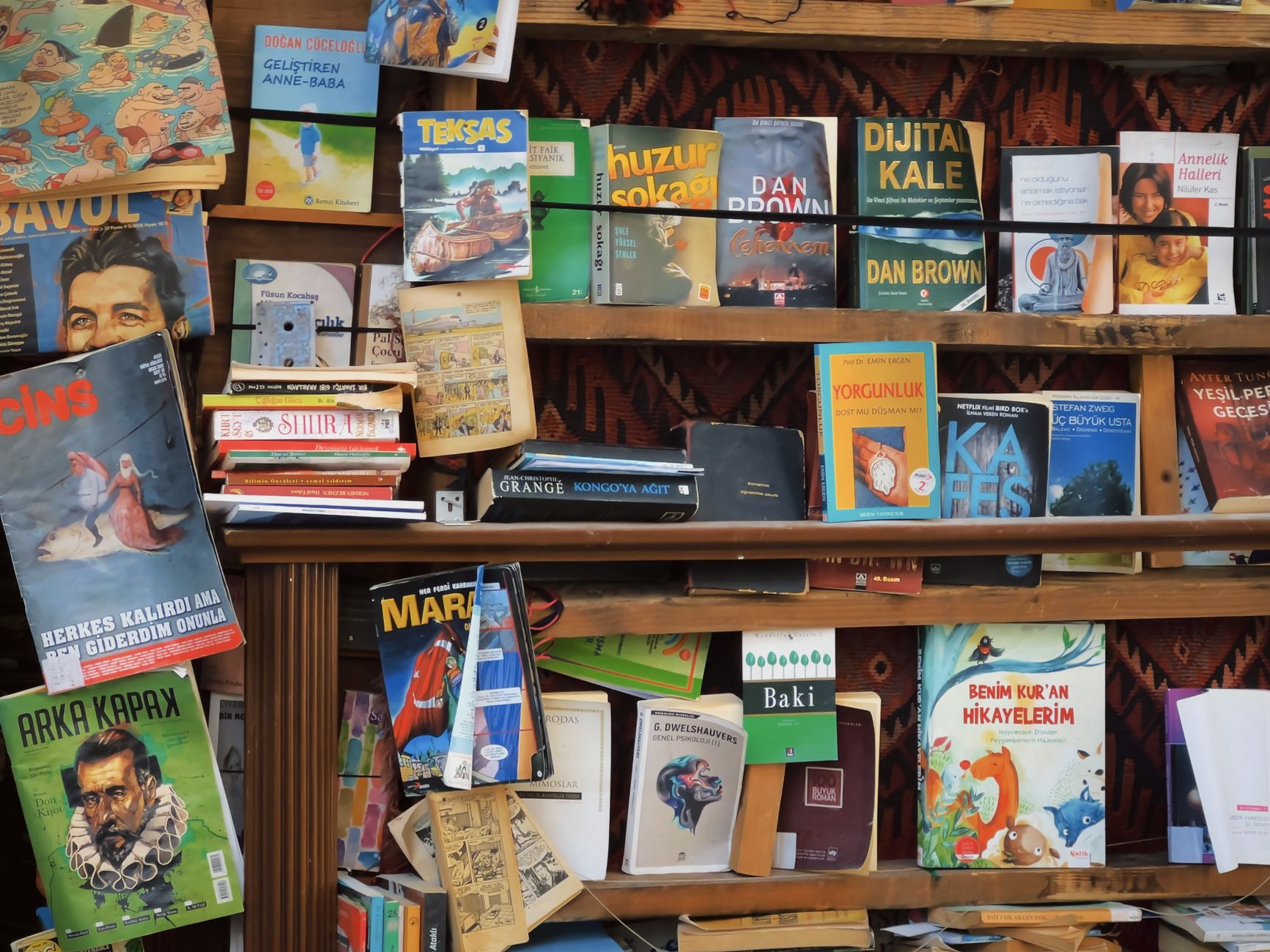 A vibrant bookshelf overflowing with books of different genres and languages.