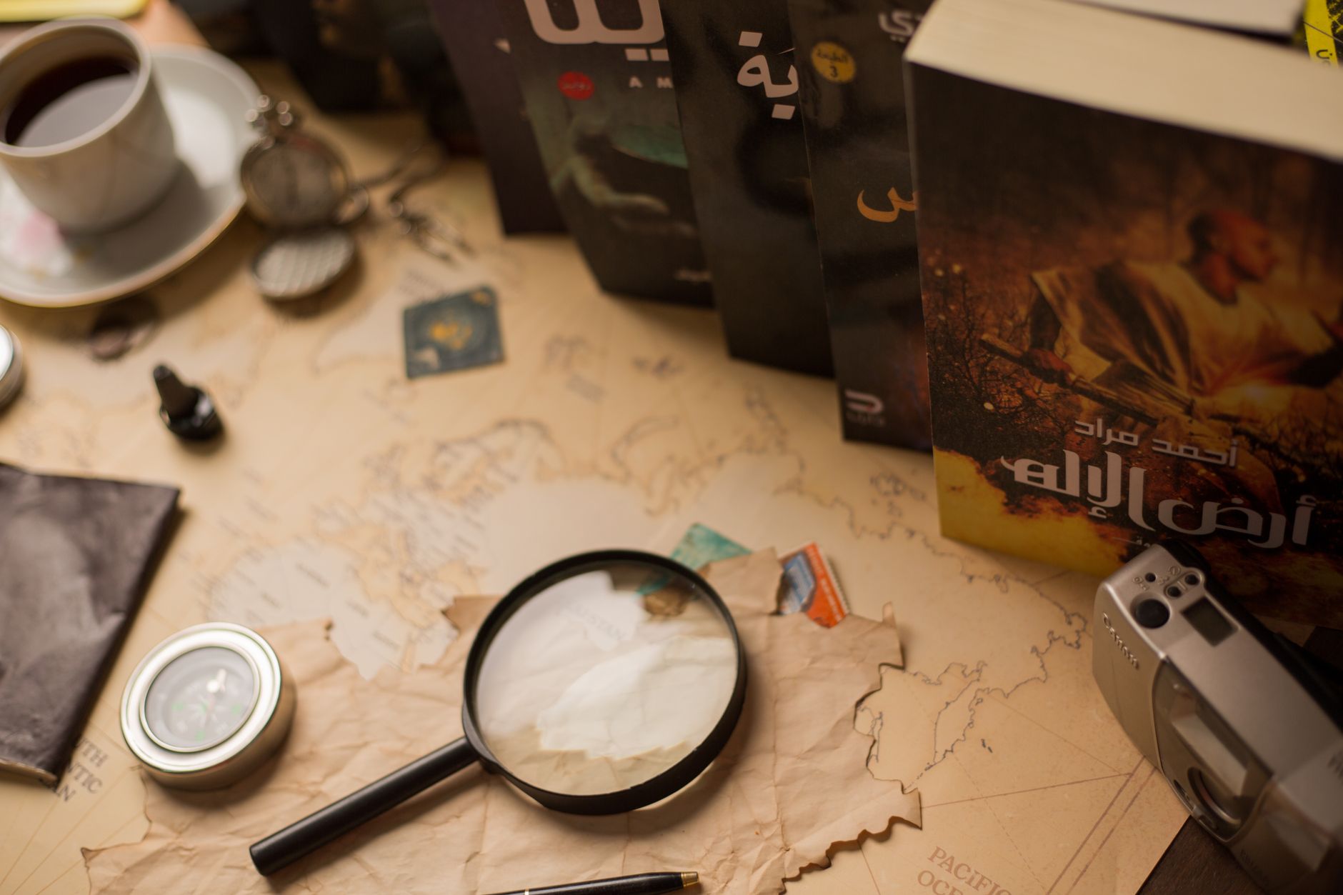 A cozy vintage desk with Arabic novels, magnifying glass, and antique compass.